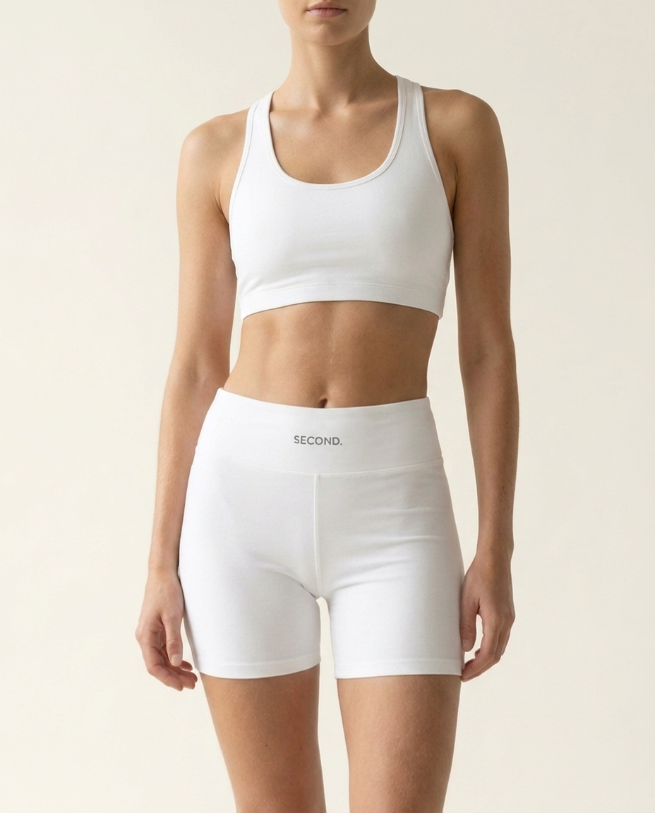 SECOND. organic cotton sports bra and bike short set in white, front view on a bone studio background